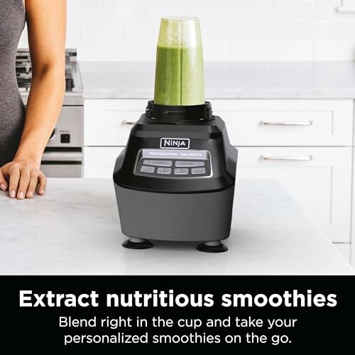 Ninja blender with green smoothie on kitchen counter.