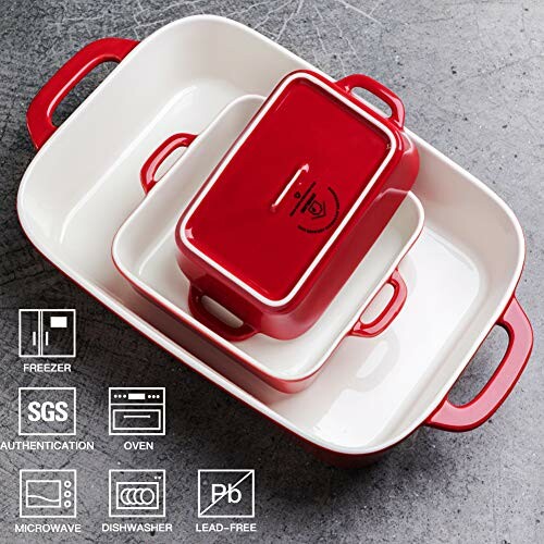 Red and white casserole dish set with lids on a gray surface.